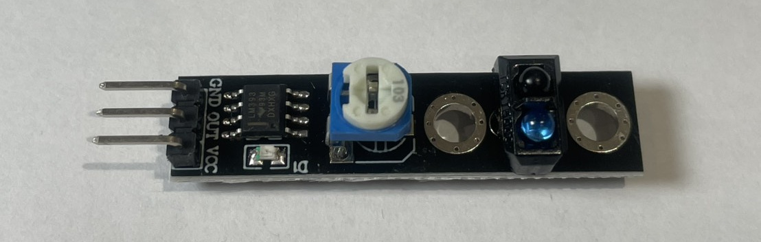 避障感測器模組的實物照。整塊黑色電路板中間偏左處，有一顆藍色的小方塊，上面是白色的十字螺絲，那顆就是可變電阻（微調電位器）。